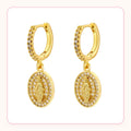 Gold huggie hoop earrings with a sparkly Virgin Mary medallion